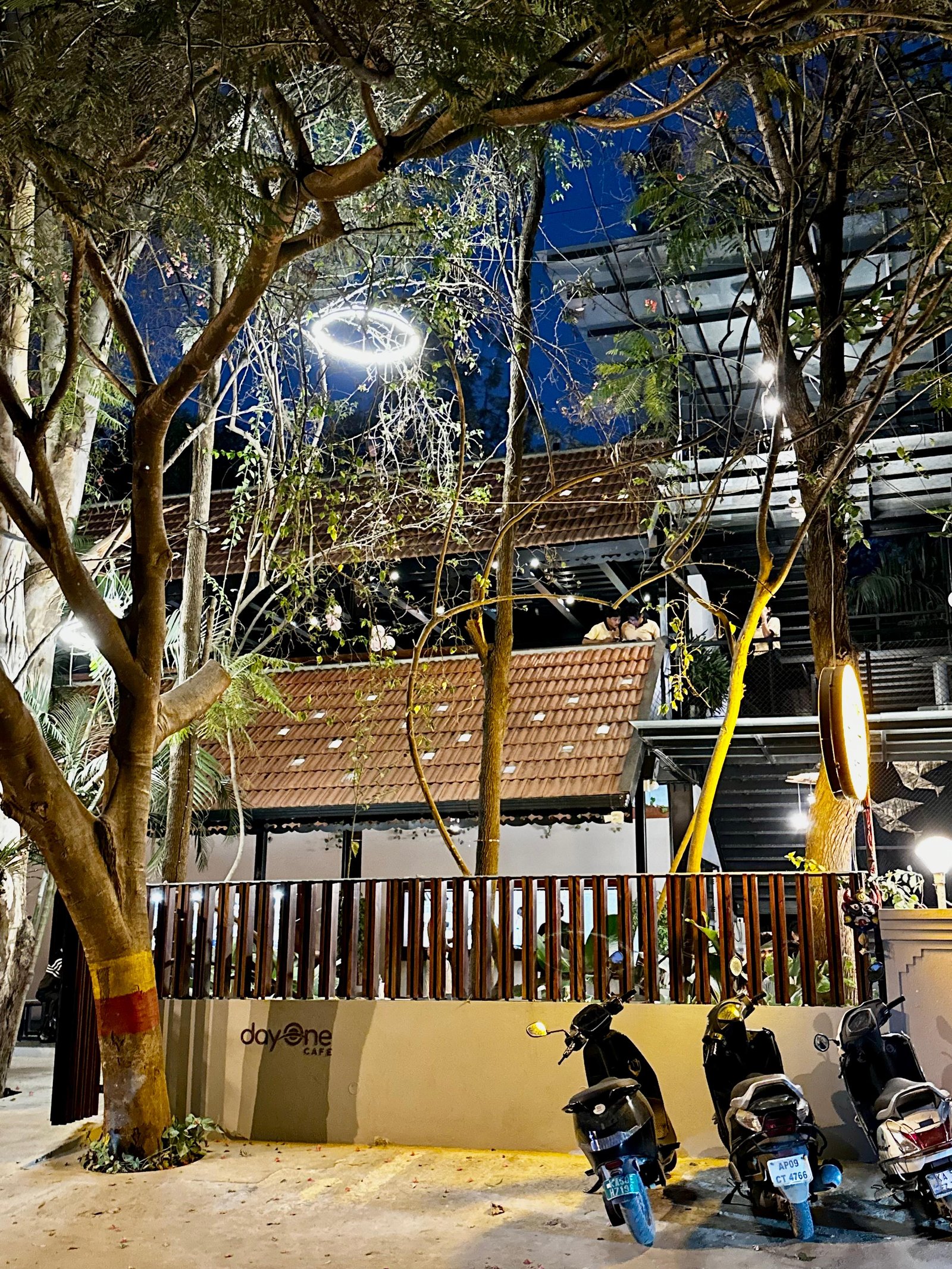 Day One Cafe open-air seating area with warm wooden tables under terracotta tile roof